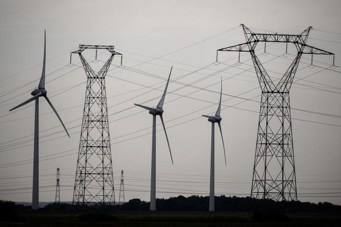 Cette photographie prise le 10 septembre 2023 montre des lignes à haute tension au milieu d'éoliennes à Soliers (Calvados)