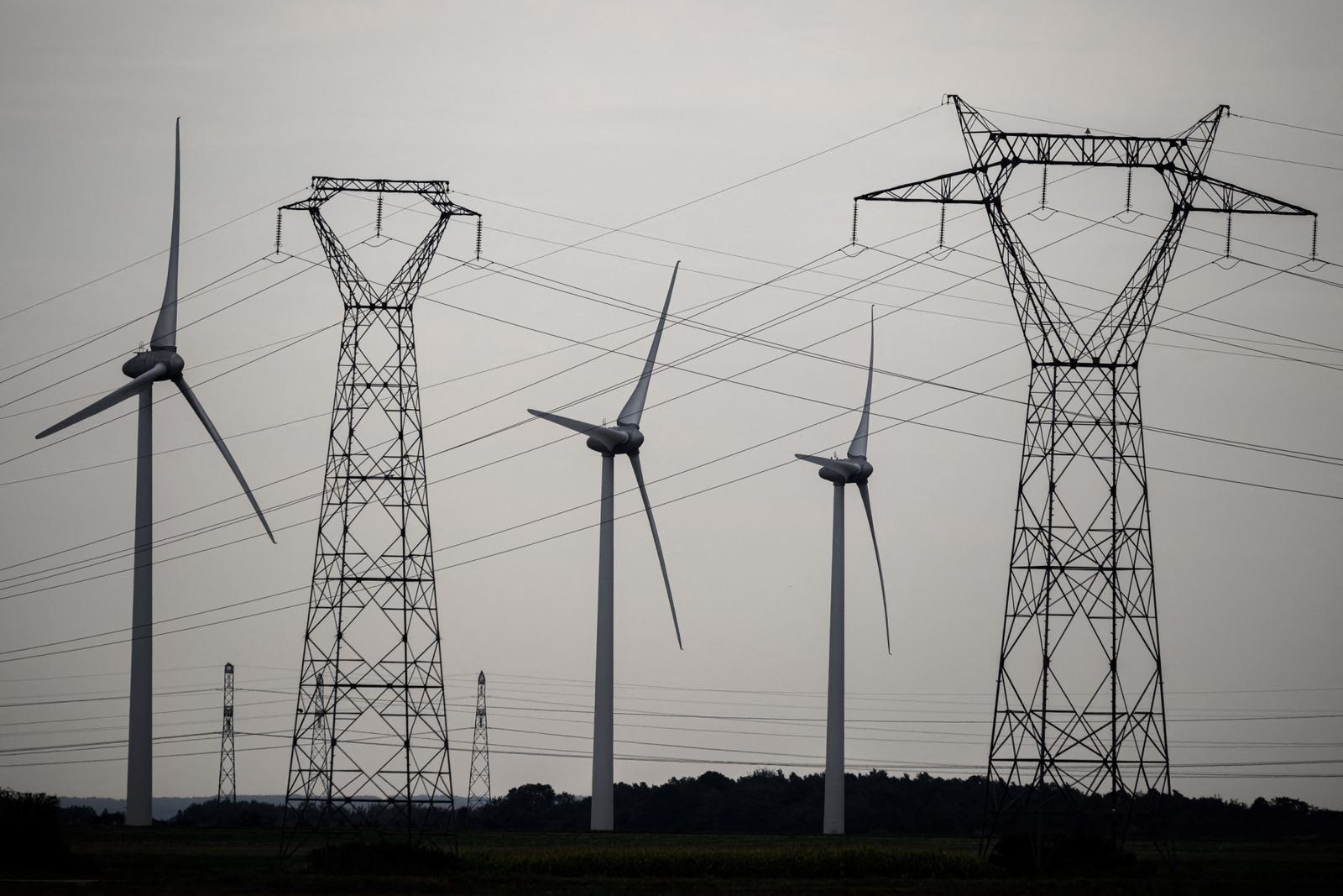 Cette photographie prise le 10 septembre 2023 montre des lignes à haute tension au milieu d'éoliennes à Soliers (Calvados)