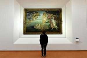 Un journaliste observe « La Naissance de Vénus », tableau peint au milieu des années 1480 par le peintre italien Sandro Botticelli, lors d'une visite de presse organisée à l'occasion de la réouverture des salles Pollaiolo et Botticelli à la Galerie des Offices de Florence, le 17 octobre 2016.