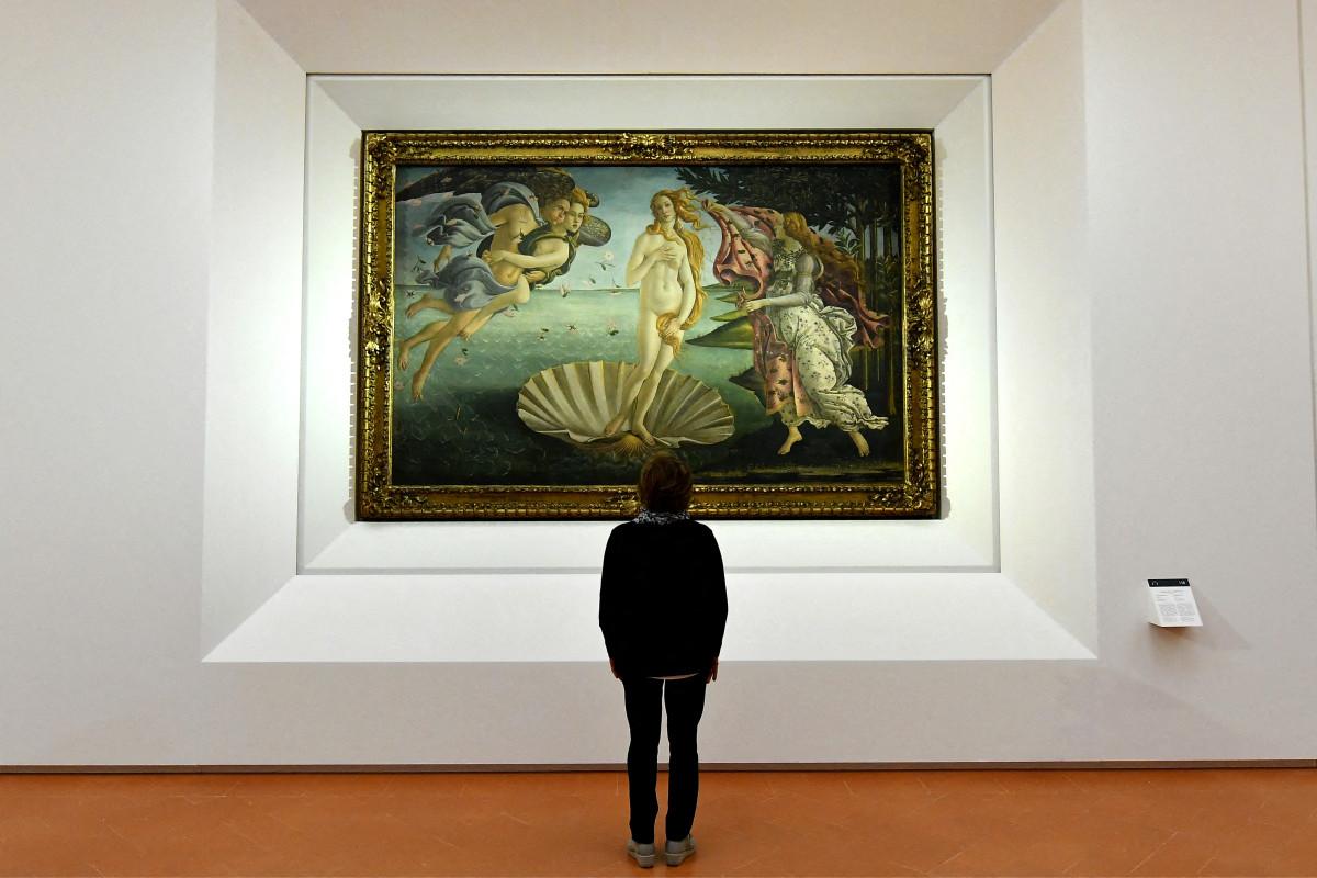 Un journaliste observe « La Naissance de Vénus », tableau peint au milieu des années 1480 par le peintre italien Sandro Botticelli, lors d'une visite de presse organisée à l'occasion de la réouverture des salles Pollaiolo et Botticelli à la Galerie des Offices de Florence, le 17 octobre 2016.