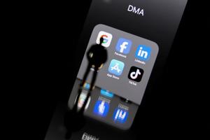 Les reflets sur l'écran d'un smartphone des logos du DMA et des plateformes en ligne Google, Facebook, LinkedIn, Amazon, Apple Store et TikTok. 