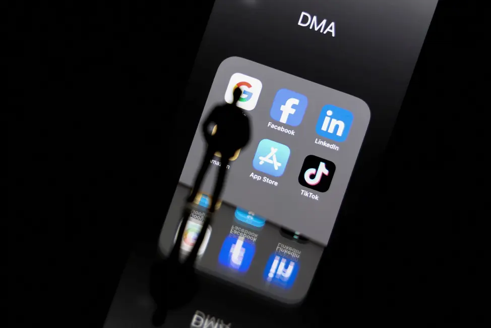 Les reflets sur l'écran d'un smartphone des logos du DMA et des plateformes en ligne Google, Facebook, LinkedIn, Amazon, Apple Store et TikTok.