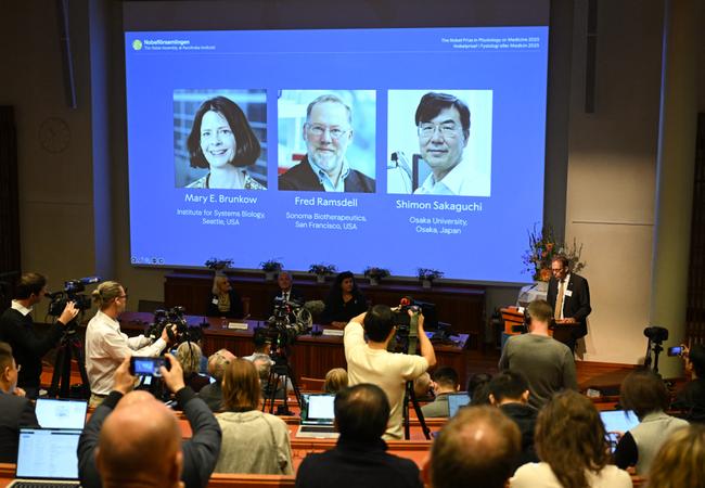 Le secrétaire général du comité Nobel, Thomas Perlmann, s'adresse aux journalistes devant un écran affichant les portraits de Mary E Brunkow, Fred Ramsdell et Shimon Sakaguchi lors d'une conférence de presse où les lauréats du prix Nobel de physiologie ou médecine 2025 sont annoncés à l'Institut Karolinska de Stockholm, en Suède, le 6 octobre 2025.