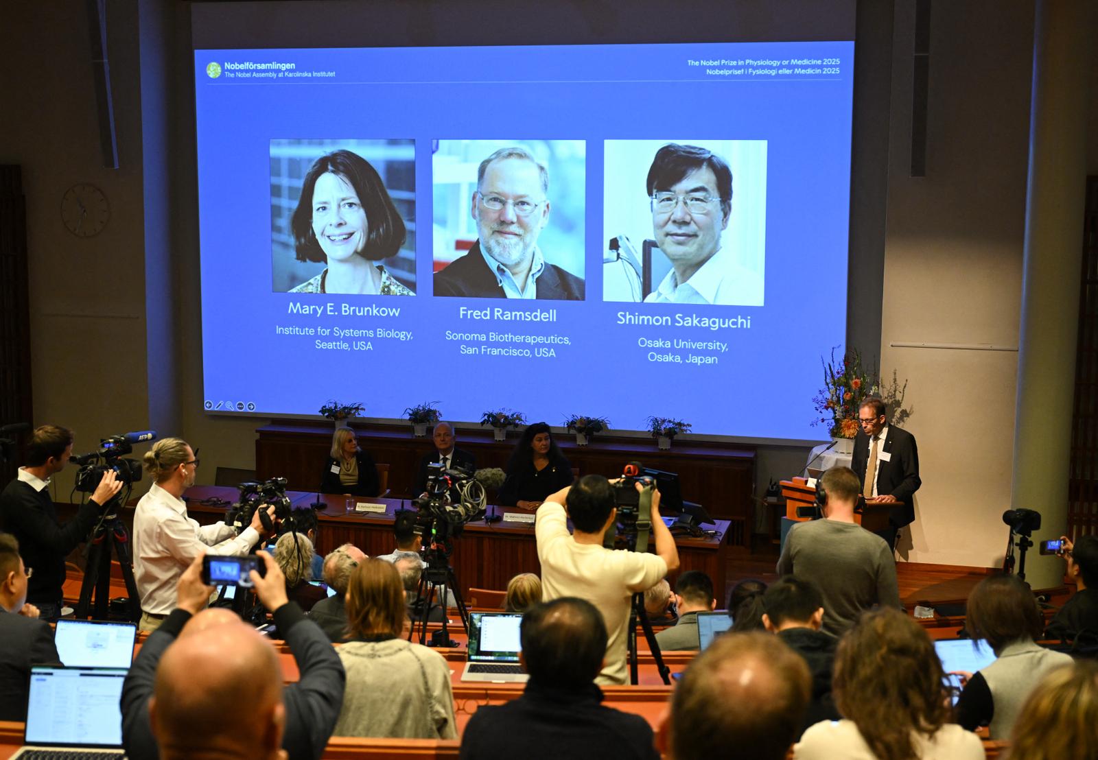 Le secrétaire général du comité Nobel, Thomas Perlmann, s'adresse aux journalistes devant un écran affichant les portraits de Mary E Brunkow, Fred Ramsdell et Shimon Sakaguchi lors d'une conférence de presse où les lauréats du prix Nobel de physiologie ou médecine 2025 sont annoncés à l'Institut Karolinska de Stockholm, en Suède, le 6 octobre 2025.