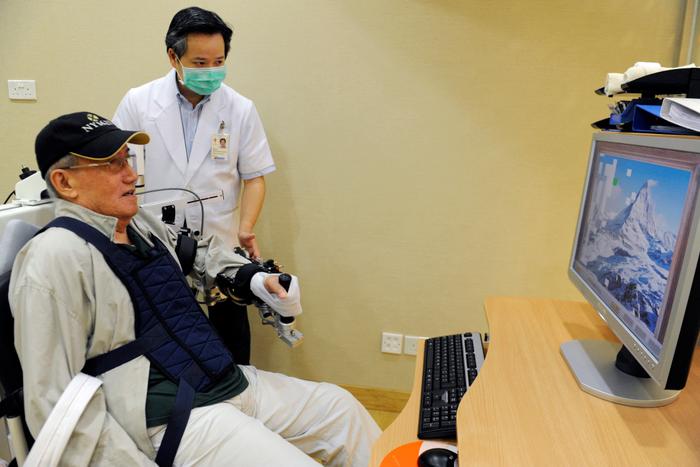Un patient âgé entraîne sa coordination œil-main grâce au bras robotisé Armeo au Centre de thérapies de réadaptation avancées de l'hôpital Tan Tock Seng de Singapour.