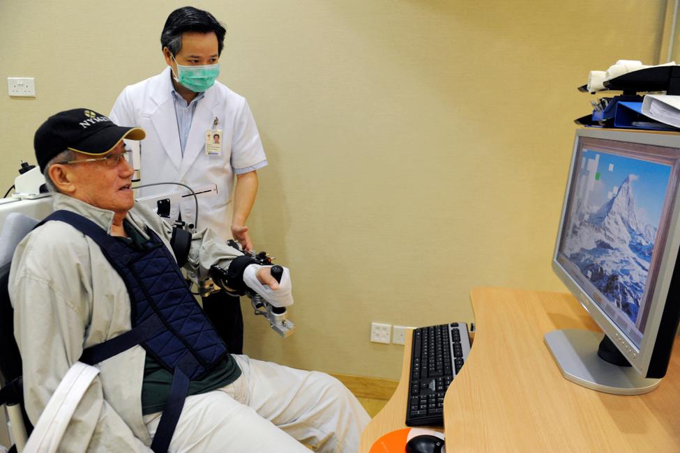 Un patient âgé entraîne sa coordination œil-main grâce au bras robotisé Armeo au Centre de thérapies de réadaptation avancées de l'hôpital Tan Tock Seng de Singapour.