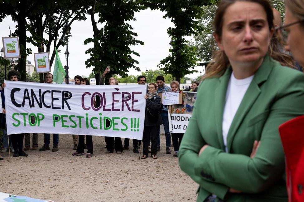 Marine Tondelier, présidente du parti Les Écologistes, se tient devant une banderole sur laquelle on peut lire « Cancer, colère, stop aux pesticides ! » lors d'une mobilisation citoyenne organisée par le collectif Nourrir devant l'Assemblée nationale, place des Invalides, à Paris, le 27 mai 2025, au lendemain du vote par les députés d'une motion de rejet du projet de loi Duplond.