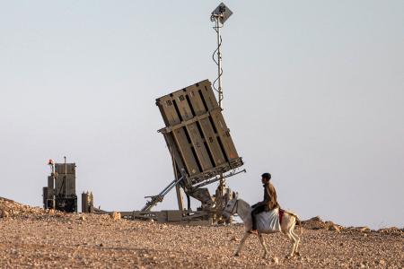 Un garçon monte un âne près d'une des batteries du système de défense antimissile israélien Dôme de fer, dans un village non reconnu par les autorités israéliennes du désert du Néguev méridional, le 14 avril 2024.