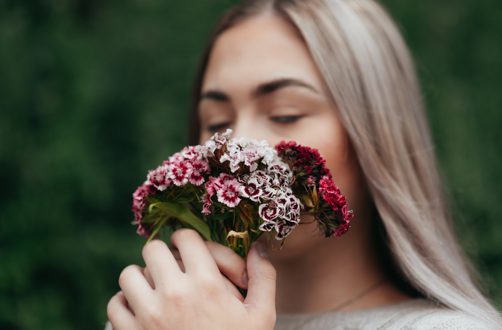 Une jeune femme sentant des fleurs. 