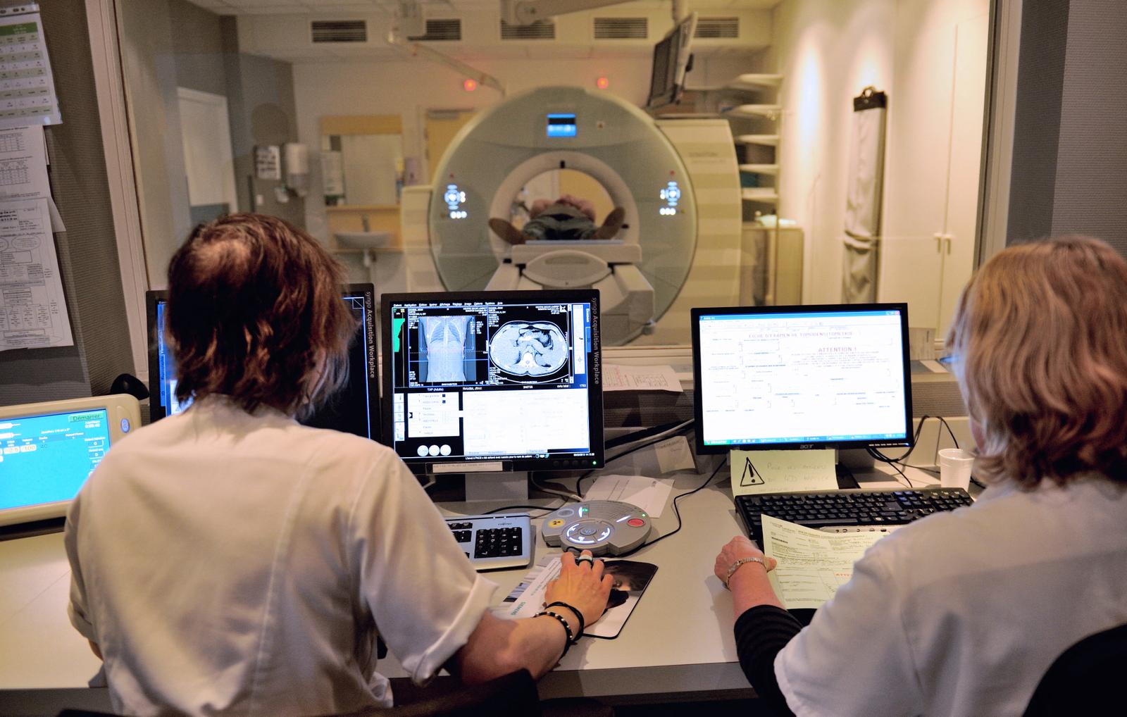 Un patient passe un scanner tandis que des techniciens en radiologie regardent l'examen sur un écran, au Centre Oscar Lambret de Lille.
